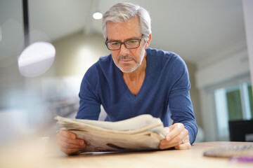 Senior man at home relaxing and reading newspaper