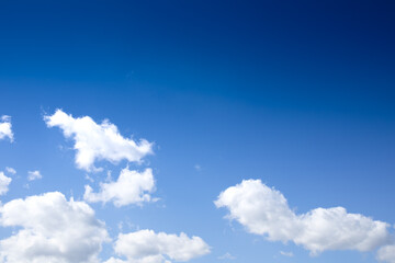 Gradient deep to bright blue sky with puffy white clouds, creative copy space, horizontal aspect