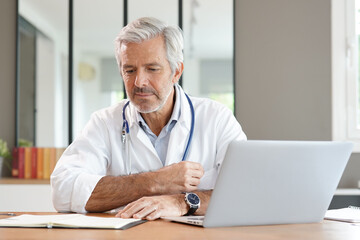 Portrait of attractive mature doctor working in office