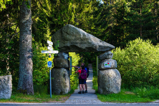 Two hikers standing at an recreation area entry looking for orientation with the help of a stationary hiking map.