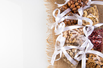 set of nuts in a gift transparent packaging tied with a white ribbon on a burlap on a white background