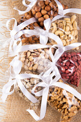 set of nuts in a gift transparent packaging tied with a white ribbon on a burlap on a white background
