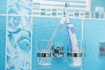 Electric toothbrush versus manual toothbrush in bathroom. Oral care and prevention concept.