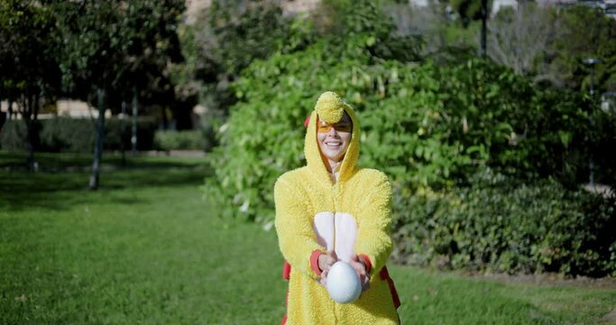 A girl dressed as a chicken throws an egg on top and catches it back. Funny video of a woman in a chicken costume. Chicken with egg. The girl and the chicken egg.