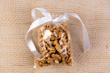 walnut in a gift transparent package tied with a white ribbon on a burlap on a white background