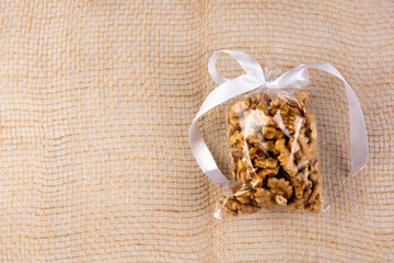 walnut in a gift transparent package tied with a white ribbon on a burlap on a white background