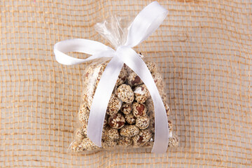 peanuts in kujut in a gift transparent package tied with a white ribbon on a burlap on a white background