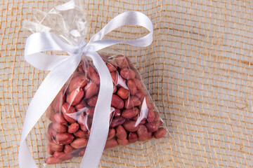 peanuts in a gift transparent package tied with a white ribbon on a burlap on a white background