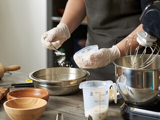 A closeup of a pastry chef adding flour
