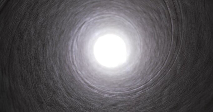 Moving through a tube tunnel with bright light shining at the end, probe lens motion, falling into a well