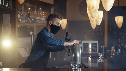 Barkeeper wearing face mask and an apron disinfecting the bar