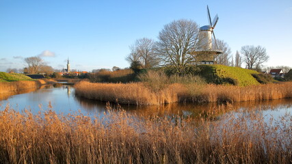 The colorful countryside surrounding Veere, Zeeland, Netherlands, with the Stadhuis (town hall) in the background (on the left) and a traditional windmill on the right