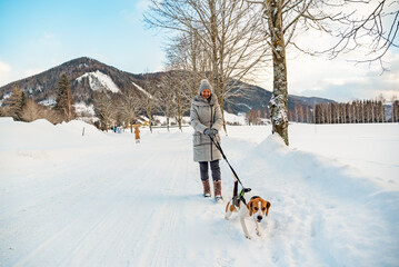 Woman with dog on a walk in winter scenery in Austria.