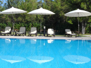 Reflection of white sun umbrellas in the swimming pool