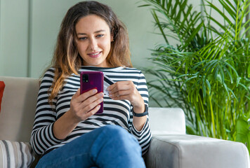 Young woman holding smartphone with credit card for pay online shopping e-commerce