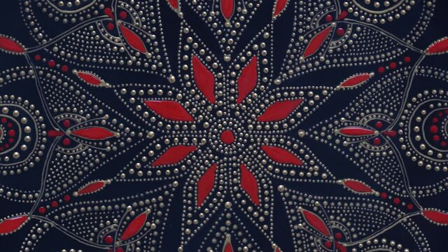 Decorative ceramic plate with black, red and golden colors, painted plate on background, closeup, top view, rotate. Decorative porcelain plate painted with acrylic paints, handwork, dot painting