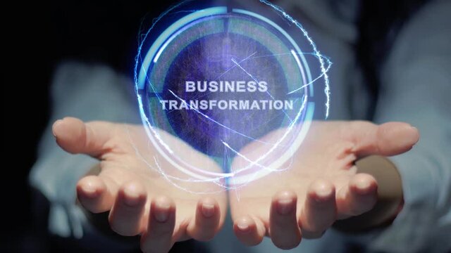 Female hands show a round conceptual hologram with text Business Transformation. Unrecognizable woman in ashen white on a black background with future holographic technology