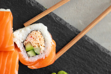 Sushi roll covered with fresh salmon served on plate