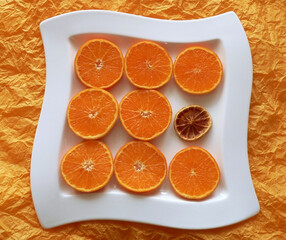 dried piece of orange between juicy pieces on white dish