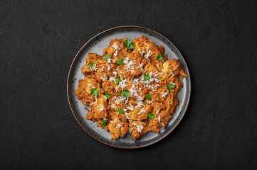 Mangalorean Chicken Sukka on black plate on dark slate table top. Indian cuisine coconut curry dish. Asian food and meal. Top view