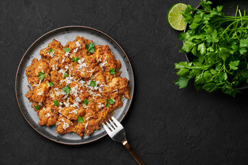 Mangalorean Chicken Sukka on black plate on dark slate table top. Indian cuisine coconut curry dish. Asian food and meal. Top view