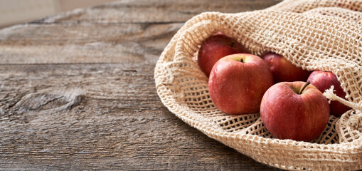 Fresh apples in an ecological reusable mesh bag made of organic cotton with copy space