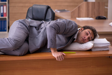 Young male employee sleeping at workplace