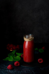 Fototapeta na wymiar Vegetarian raspberry smoothie in a glass bottle on a dark background