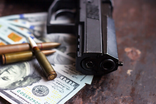 Black gun and bullets on American dollars background. Military industry, war, global arms trade, weapon sale, contract killing and crime concept.