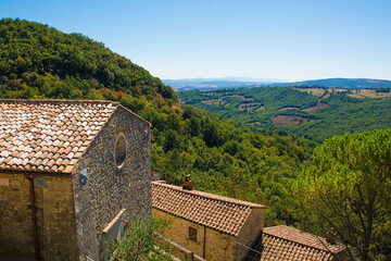 Fototapeta na wymiar A view of the landscape over rooftops in the historic medieval village of Rocchette di Fazio near Semproniano in Grosseto Province, Tuscany, Italy 