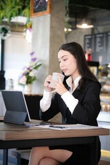 Portrait of attractive businesswoman in formal suit taking a break drinking hot beverage at modern cafe.