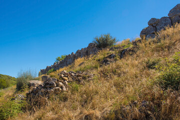 Fototapeta na wymiar The ruins of the Etruscan Perimeter Walls in Roselle or Rusellae, an ancient Etruscan and Roman city in Tuscany. These cyclopean dry stone walls were made from irregular blocks