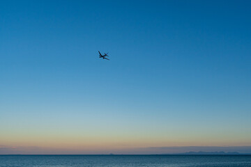 Fototapeta na wymiar 夕暮れ時の空を上昇していく飛行機