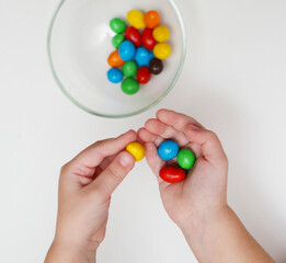 The child chooses multi-colored chocolates. The sweet tooth is looking for sweet candy. Celebration of chocolate.