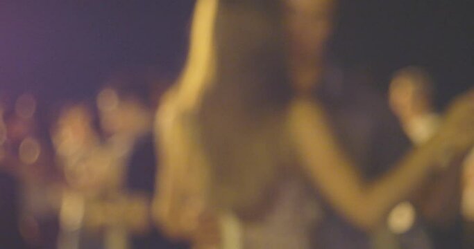 Pairs dancing mamba outside in the night street. Defocused shot of salsa dance outdoors.
