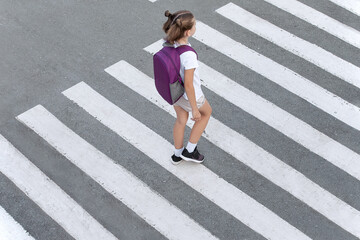 Schoolgirl crossing road on way to school. Zebra traffic walk way in the city. Concept pedestrians...