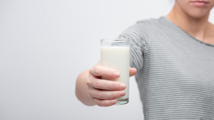 Powerfull woman squeezes hard a glass of milk in her naked hand. front view