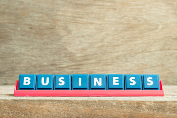 Tile letter on red rack in word business on wood background