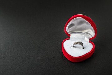 Silver engagement ring in red heart-shaped velvet box. Accessory with gems. Romantic gift. Precious...