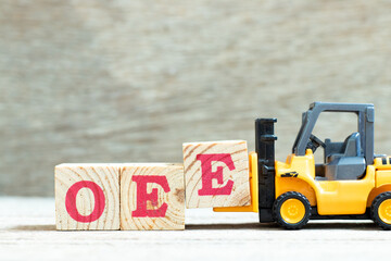 Toy forklift hold letter block E to complete word OEE (abbreviation of overall equipment...