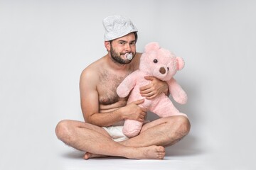 Infant adult man with pacifier in diaper holding pink teddy bear