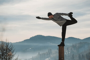 Man doing yoga exercises in front of amazing sunset on the winter mountains. Copy, empty space for...