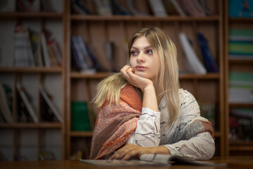 A young blonde beautiful girl spends time in a public library.