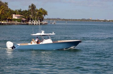 Fototapeta na wymiar Light blue, upscale open sport fishing boat cruising the Florida Intra-Coastal Waterway.