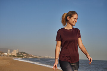 Fototapeta na wymiar Smiling young woman walking on the beach
