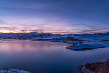 Beautiful winter landscape. Panoramic view on the lake  and mountains peaks snow-covered  after sunset. 