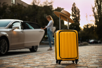 Woman near taxi outdoors, focus on suitcase