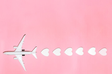 Happy Valentine's Day. White passenger plane with hearts on pink background. Flat lay vacation planing and traveling holiday. Holiday travel concept. Top view
