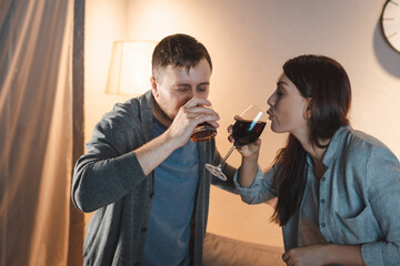 alcohol-addicted couple drinking whiskey and wine at home together