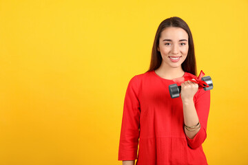 Woman with dumbbell as symbol of girl power on yellow background, space for text. 8 March concept